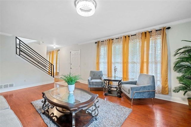 living room with baseboards, visible vents, stairway, ornamental molding, and wood finished floors