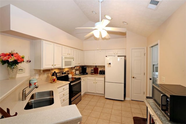 kitchen featuring white appliances, a sink, vaulted ceiling, white cabinetry, and tasteful backsplash