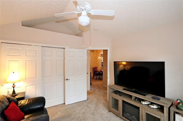 living area featuring a ceiling fan, vaulted ceiling, and light colored carpet