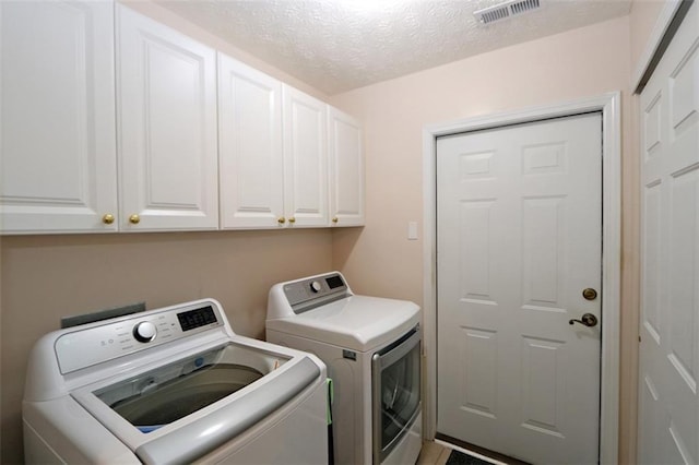 laundry area featuring visible vents, cabinet space, separate washer and dryer, and a textured ceiling