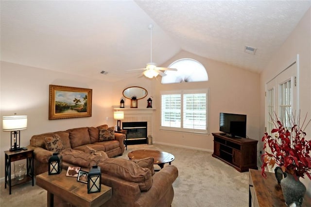 living area featuring visible vents, light colored carpet, a tiled fireplace, and vaulted ceiling