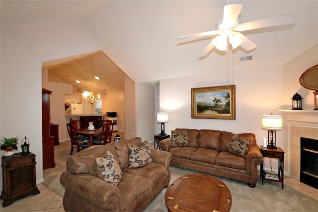 living area featuring visible vents, lofted ceiling, ceiling fan with notable chandelier, a fireplace, and light colored carpet