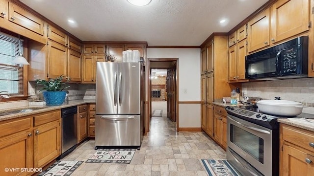 kitchen with sink, stainless steel appliances, light stone countertops, a textured ceiling, and decorative backsplash