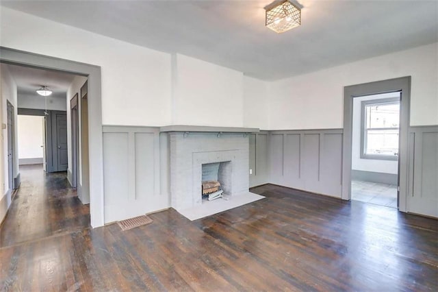 1497 Rogers Ave, Atlanta, GA 30310 - unfurnished living room featuring a decorative wall, wood finished floors, a wainscoted wall, and a fireplace