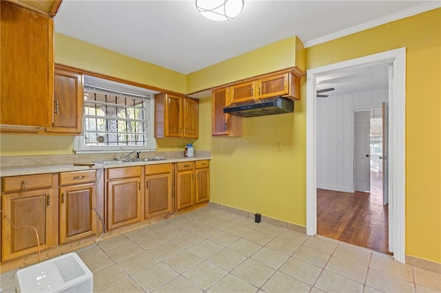2081 Dodson Dr SW, Atlanta, GA 30311 - kitchen with under cabinet range hood, brown cabinetry, light countertops, light tile patterned floors, and a sink