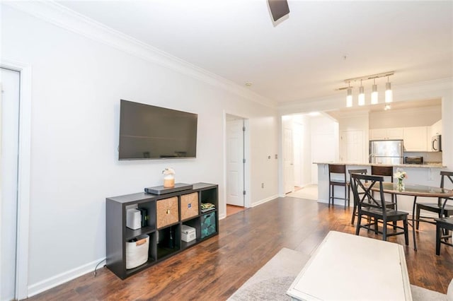 living room with ornamental molding, wood finished floors, and baseboards