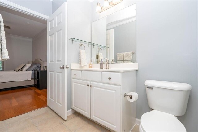 ensuite bathroom featuring crown molding, toilet, vanity, and tile patterned flooring