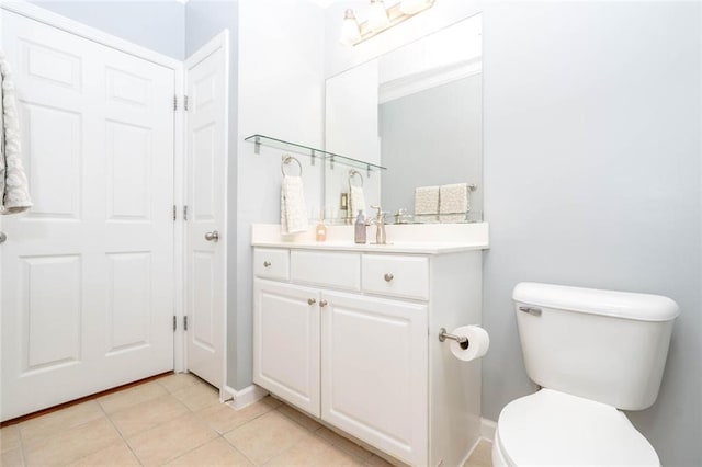 bathroom with toilet, tile patterned flooring, vanity, and baseboards