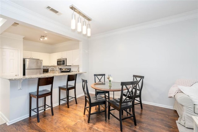 dining space featuring ornamental molding, dark wood-type flooring, and baseboards
