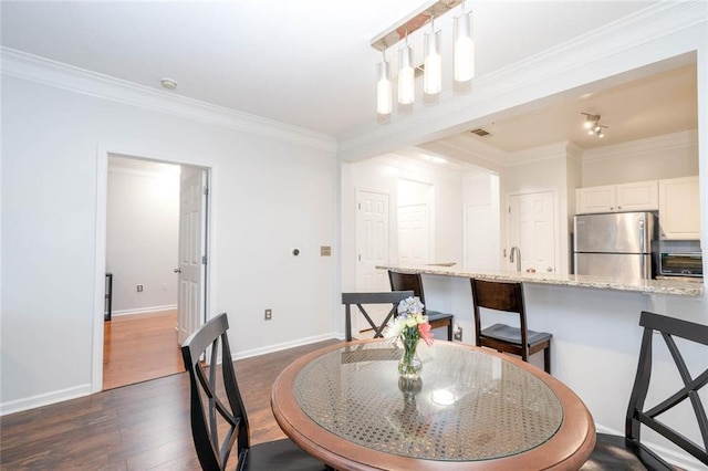 dining area with ornamental molding, dark wood finished floors, and baseboards