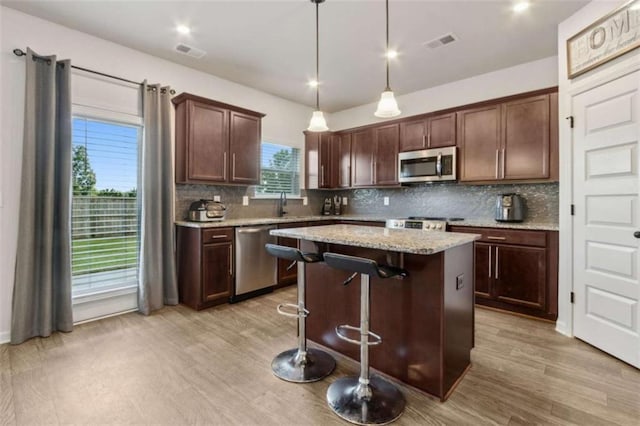1130 Lyndhurst Ln, Bethlehem, GA 30620 - kitchen featuring appliances with stainless steel finishes, decorative backsplash, a center island, and a kitchen breakfast bar