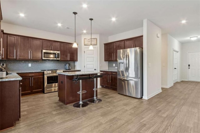 1130 Lyndhurst Ln, Bethlehem, GA 30620 - kitchen with appliances with stainless steel finishes, decorative backsplash, light wood finished floors, a kitchen island, and a breakfast bar area