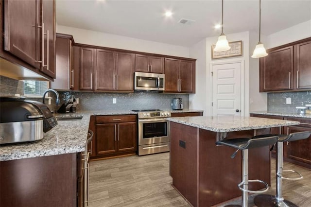 1130 Lyndhurst Ln, Bethlehem, GA 30620 - kitchen with stainless steel appliances, a kitchen island, tasteful backsplash, a breakfast bar, and light wood finished floors
