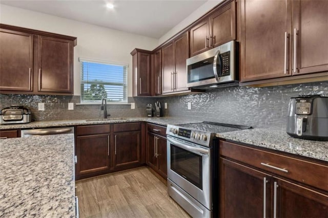 1130 Lyndhurst Ln, Bethlehem, GA 30620 - kitchen with appliances with stainless steel finishes, light stone counters, decorative backsplash, light wood-style flooring, and dark brown cabinets
