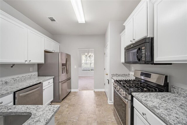 kitchen featuring white cabinets, light stone counters, appliances with stainless steel finishes, and a chandelier