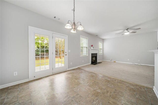 unfurnished living room featuring carpet flooring, plenty of natural light, and ceiling fan with notable chandelier