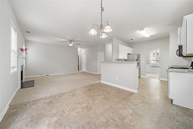 kitchen featuring white cabinetry, stainless steel fridge, decorative light fixtures, light carpet, and ceiling fan with notable chandelier