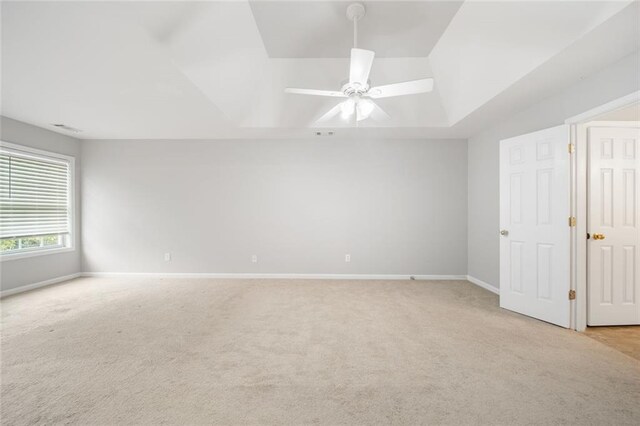 unfurnished bedroom with a raised ceiling, ceiling fan, and light colored carpet