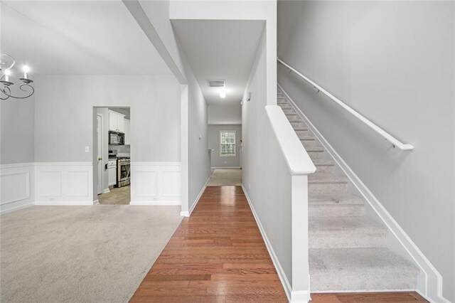 staircase with hardwood / wood-style flooring and an inviting chandelier