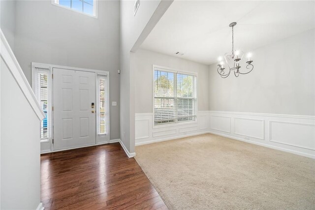 entryway featuring a towering ceiling, dark hardwood / wood-style flooring, a wealth of natural light, and a notable chandelier