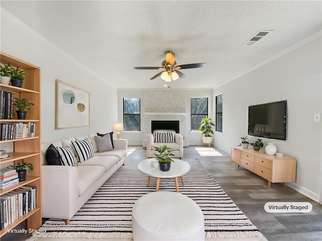 living area with visible vents, a fireplace, wood finished floors, and ornamental molding