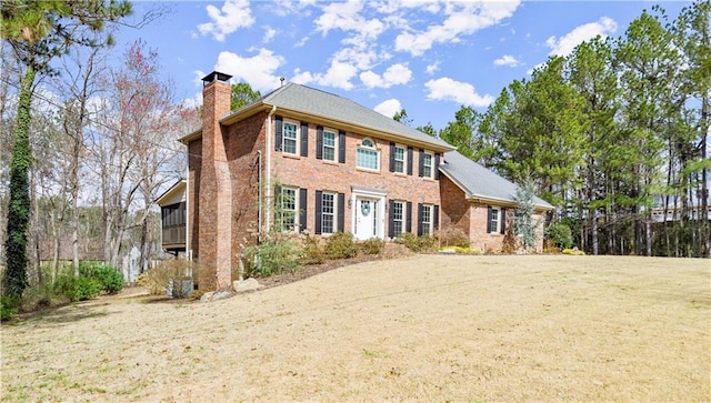 colonial home with a front lawn, brick siding, and a chimney