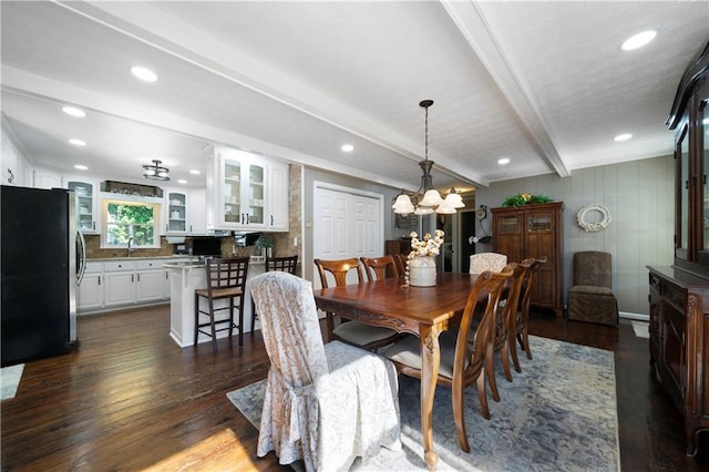 dining space with dark wood-type flooring, beamed ceiling, and a chandelier