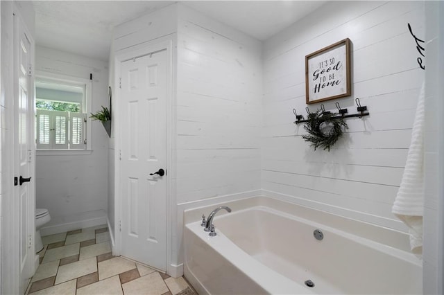 bathroom featuring toilet, tile patterned flooring, and a bath