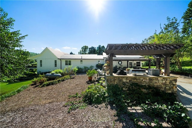 rear view of property featuring a pergola, area for grilling, and a bar