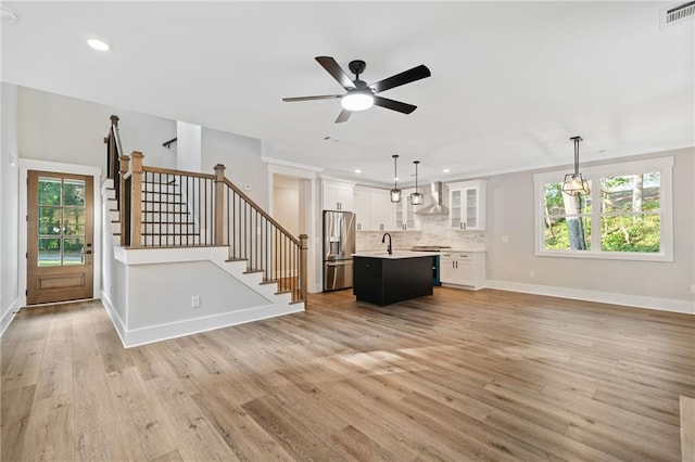 unfurnished living room featuring light hardwood / wood-style floors, sink, and ceiling fan