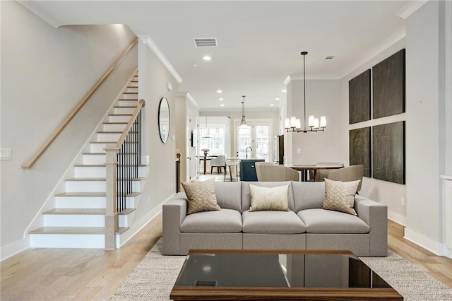 living room featuring light wood-style flooring, stairway, visible vents, and crown molding