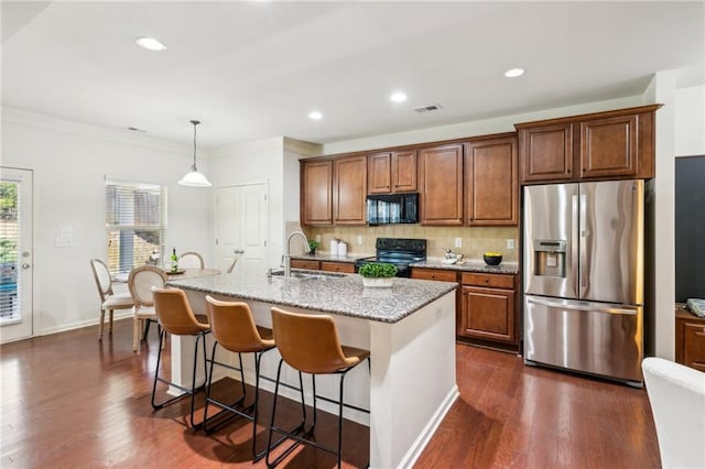 kitchen with a sink, light stone counters, decorative backsplash, black appliances, and dark wood-style flooring