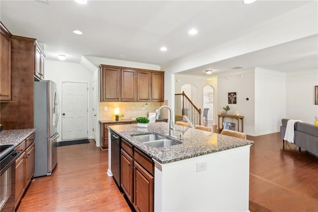 kitchen with a sink, freestanding refrigerator, stone counters, stove, and dishwasher