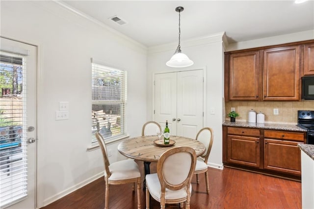 dining area featuring baseboards, dark wood-style floors, visible vents, and ornamental molding