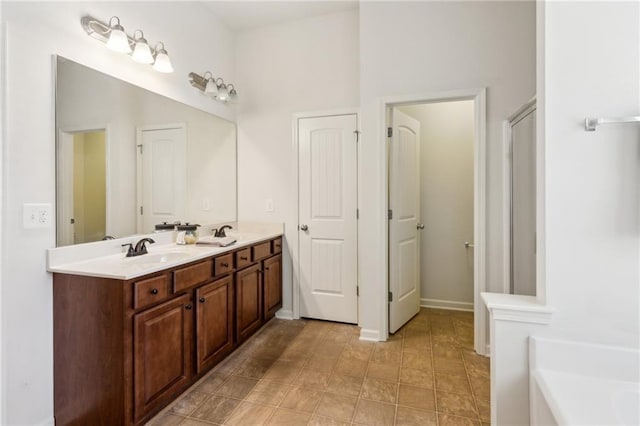 bathroom with double vanity, baseboards, a garden tub, and a sink