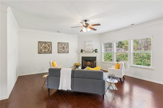 living area with baseboards, visible vents, dark wood finished floors, a lit fireplace, and ornamental molding