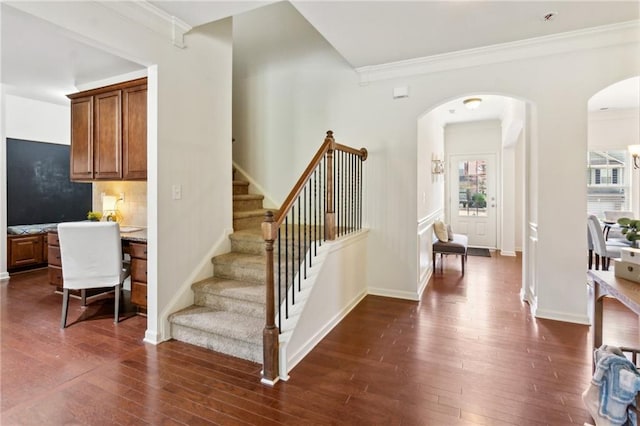 stairs featuring arched walkways, baseboards, and hardwood / wood-style floors