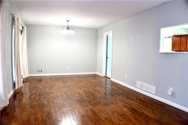 unfurnished room featuring dark wood-type flooring and a notable chandelier