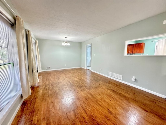 spare room featuring wood-type flooring, a textured ceiling, and an inviting chandelier