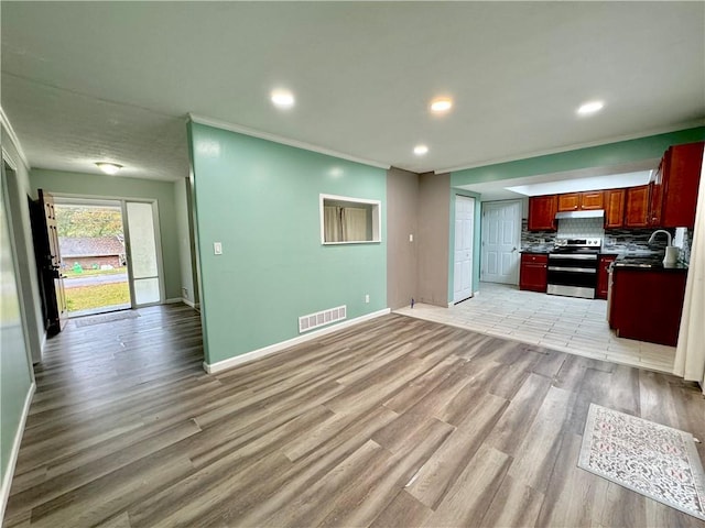 kitchen with stainless steel electric range, light hardwood / wood-style floors, sink, and tasteful backsplash