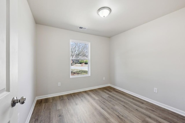 spare room with visible vents, baseboards, and wood finished floors