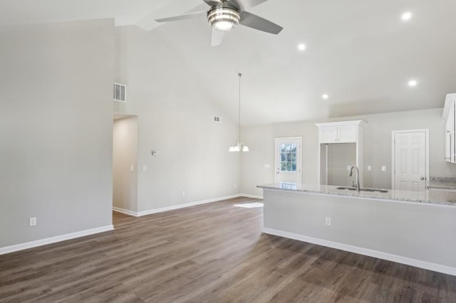 kitchen featuring white cabinets, a sink, dark wood finished floors, ceiling fan with notable chandelier, and light stone counters