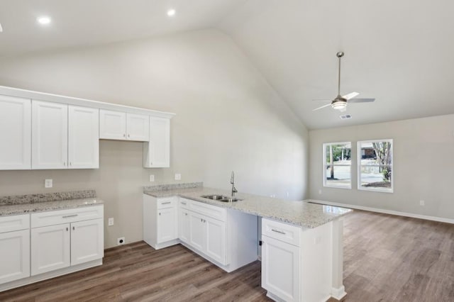 kitchen with white cabinets, a sink, open floor plan, ceiling fan, and wood finished floors