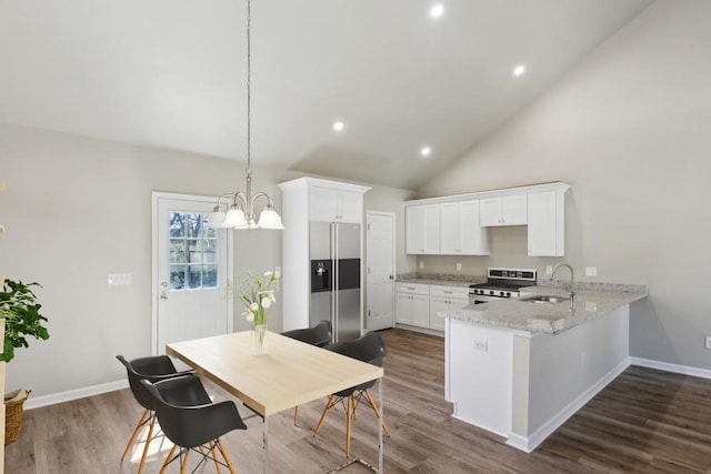 kitchen featuring stainless steel appliances, a peninsula, dark wood-style flooring, a sink, and white cabinetry