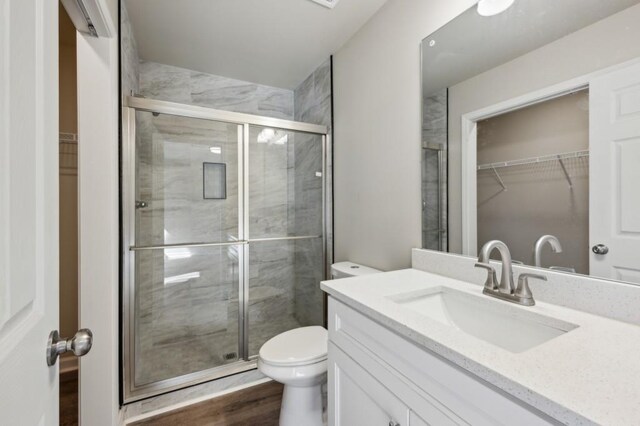 bathroom featuring a spacious closet, a stall shower, vanity, and toilet