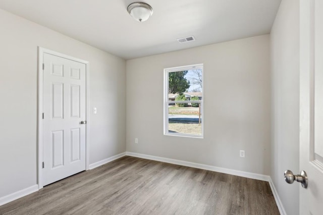 empty room with visible vents, baseboards, and wood finished floors