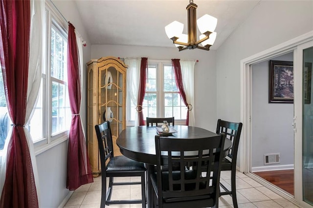 dining room with lofted ceiling, light tile patterned floors, a healthy amount of sunlight, and an inviting chandelier