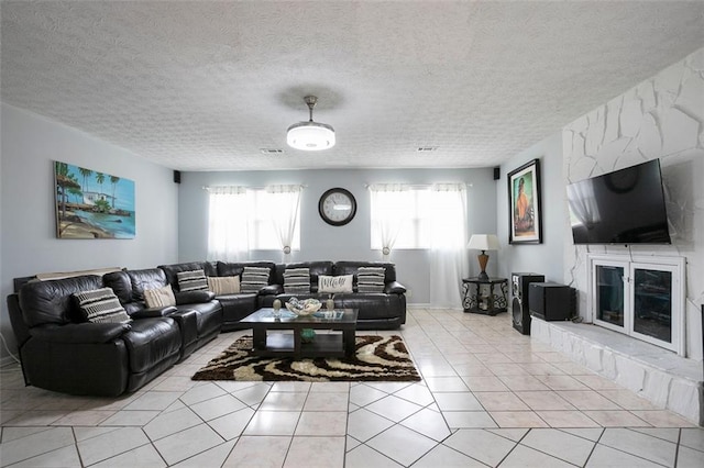 living room with light tile patterned flooring, a large fireplace, and a textured ceiling