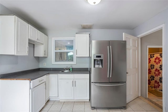 kitchen with white cabinetry, sink, stainless steel fridge, and light tile patterned flooring