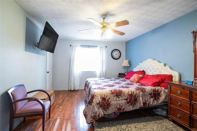 bedroom with hardwood / wood-style flooring, ceiling fan, and a textured ceiling